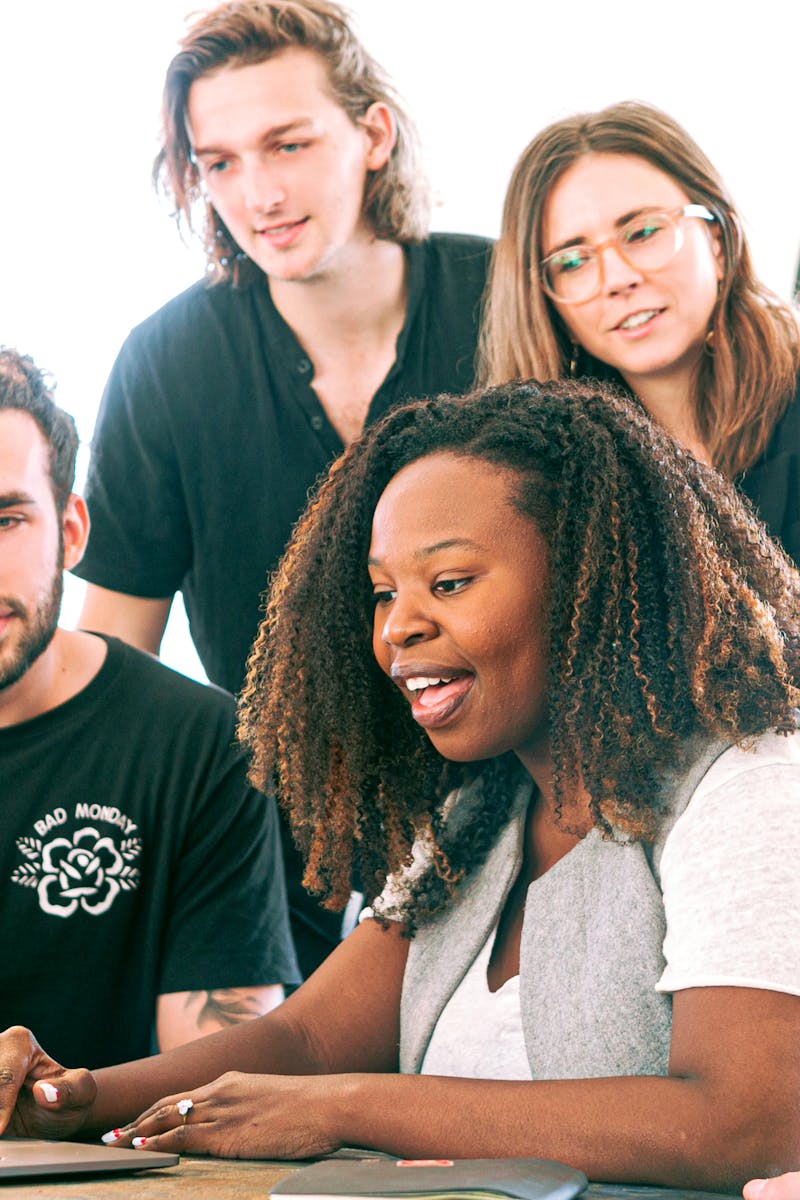 A diverse group of young professionals collaborating around a laptop in a modern office setting. Perfect for business or tech concepts.